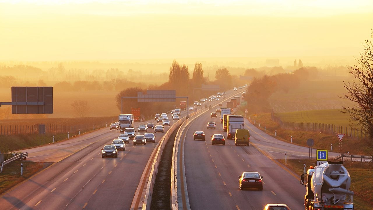 Voiture rouge circulant sur une route au bord d'une rivière