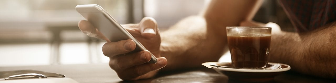 homme avec le café sur le téléphone portable