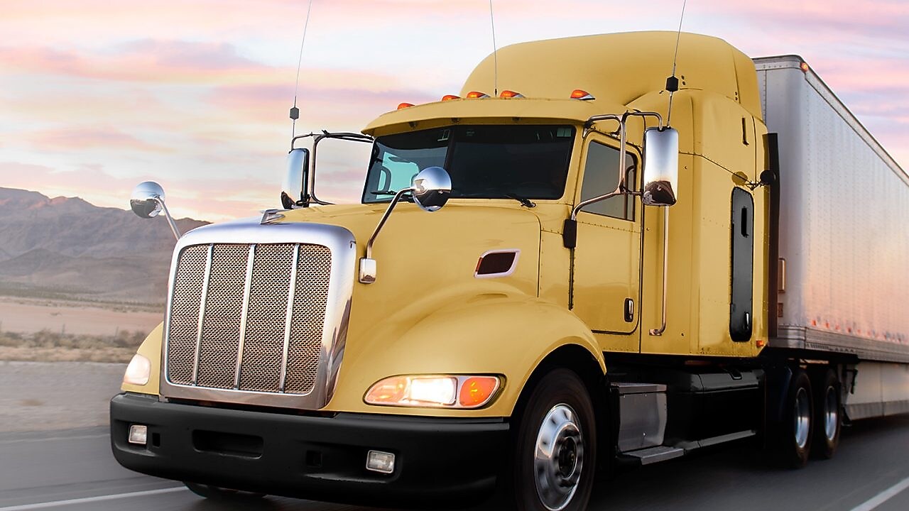 a yellow truck driving down a road at dusk