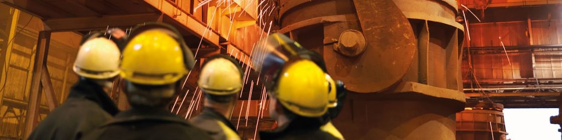 ouvriers observant une machine dans une usine de métallurgie