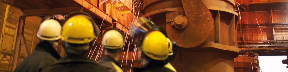 ouvriers observant une machine dans une usine de métallurgie