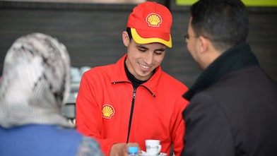 Champion de service Shell en train de servir un café à des clients 