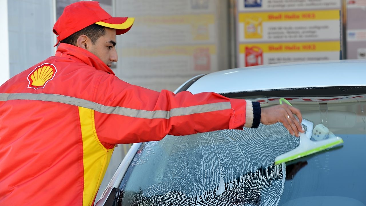 Champion de service Shell en train de nettoyer un pare-brise