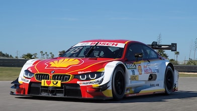 Une voiture de course BMW rouge et blanche se trouve sur la piste, illustrant le Partenariat technologique premium entre Shell Helix Ultra et BMW