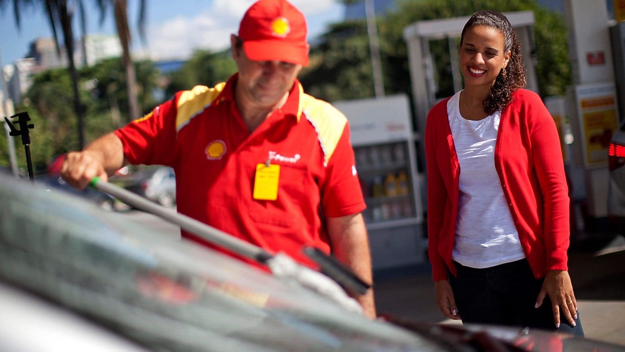 Champion de service Shell en train de nettoyer un pare-brise