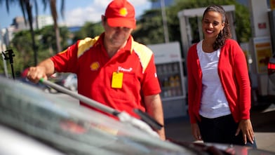 Champion de service Shell en train de nettoyer un pare-brise